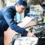 A mechanic is shown inspecting under the hood of a vehicle while performing an auto service.