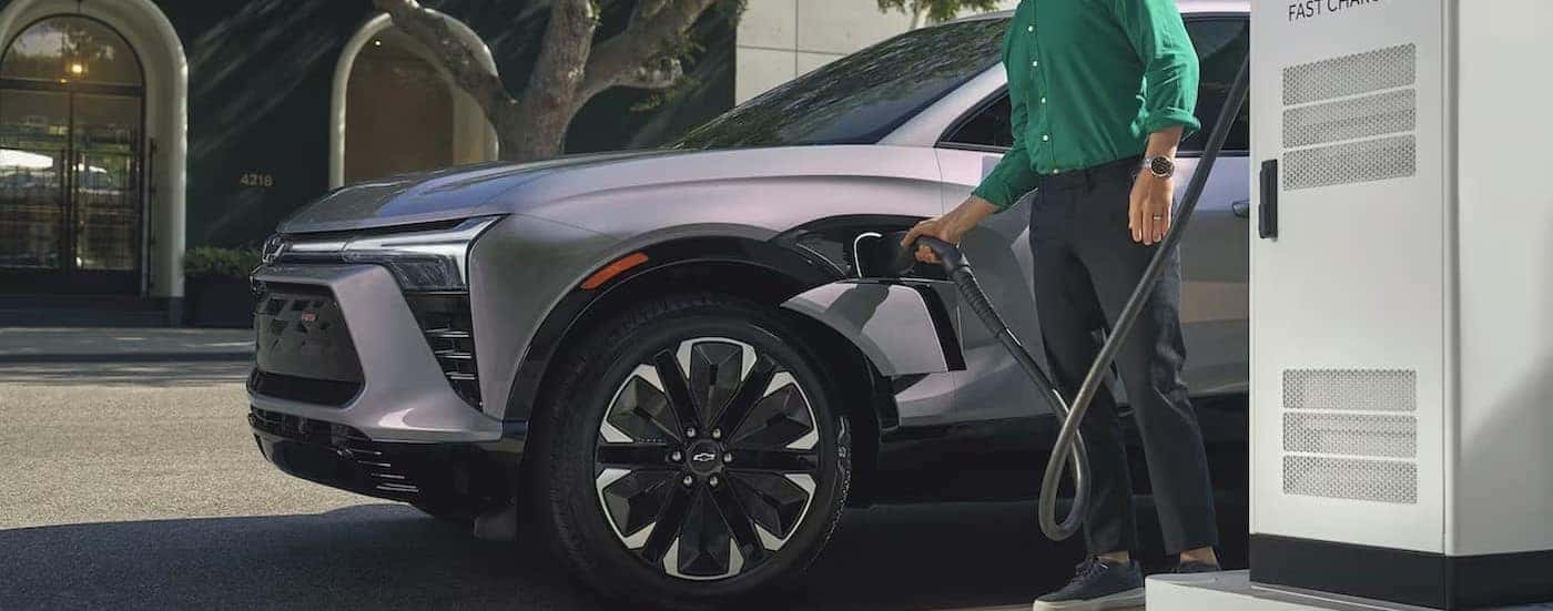 A silver 2024 Chevy Blazer EV RS is shown charging at a charging station.