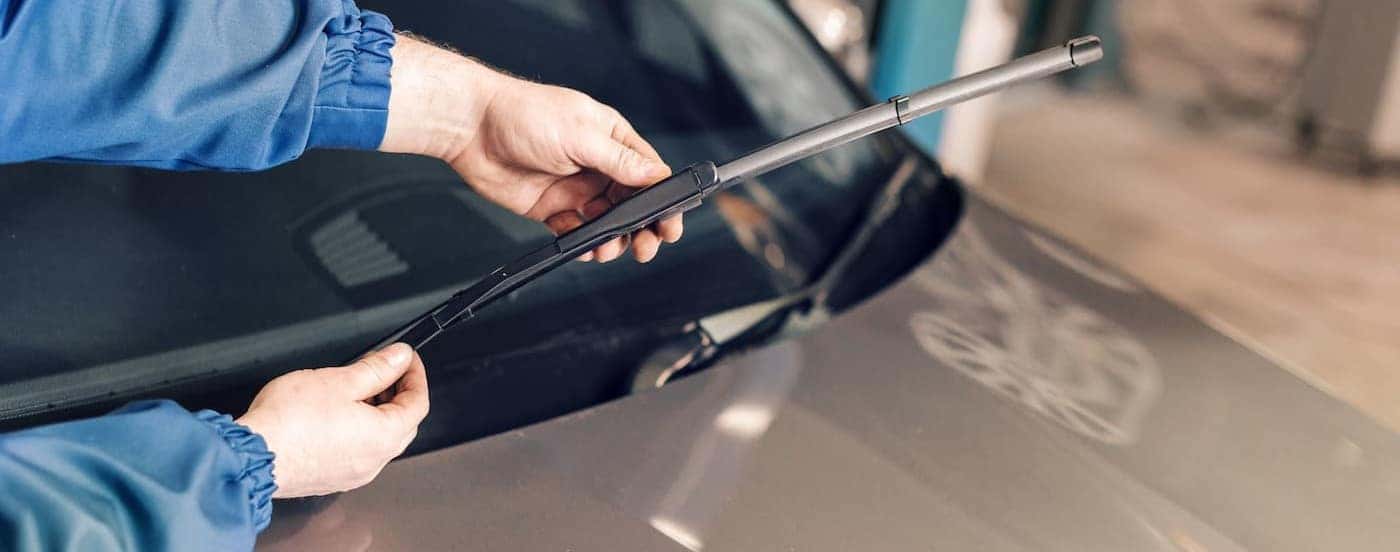 A mechanic is shown holding a windshield wiper blade.