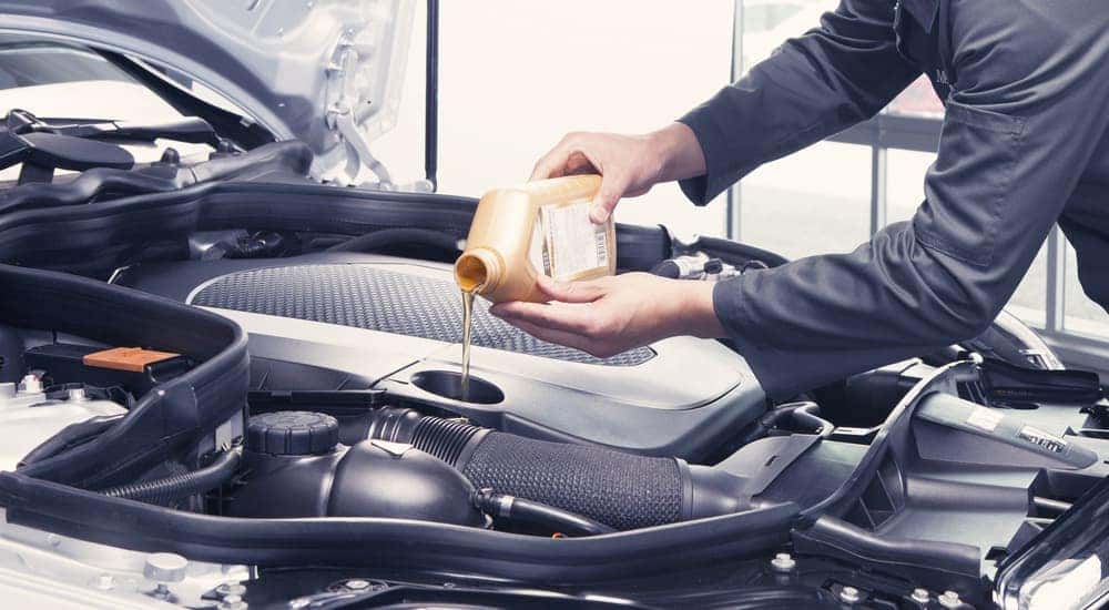 A mechanic is shown pouring oil into an engine.