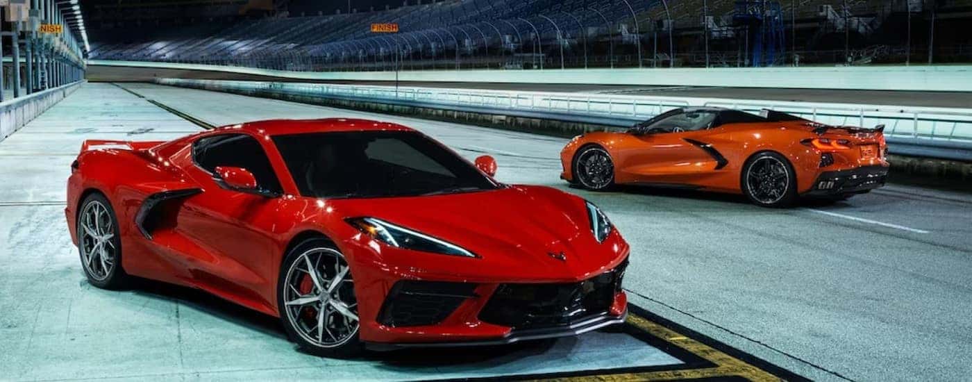 A red and an Orange 2024 Chevy Corvette Stingray 3 LT Coupe's are shown parked on a racetrack.