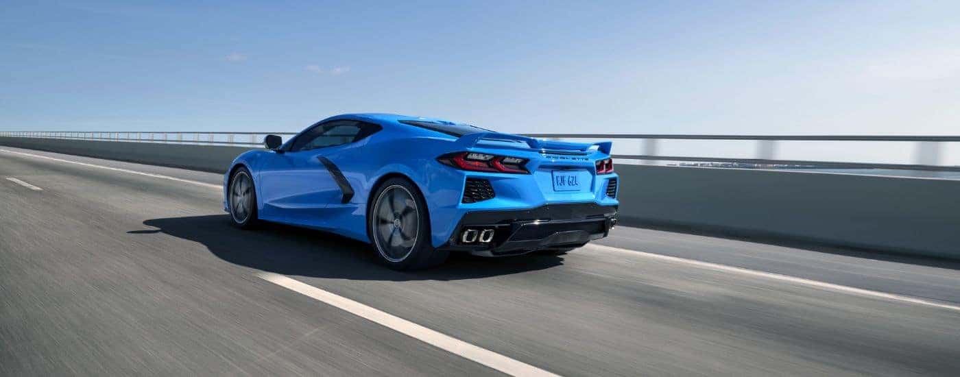 A blue 2024 Chevy Corvette Stingray is shown driving on a bridge.