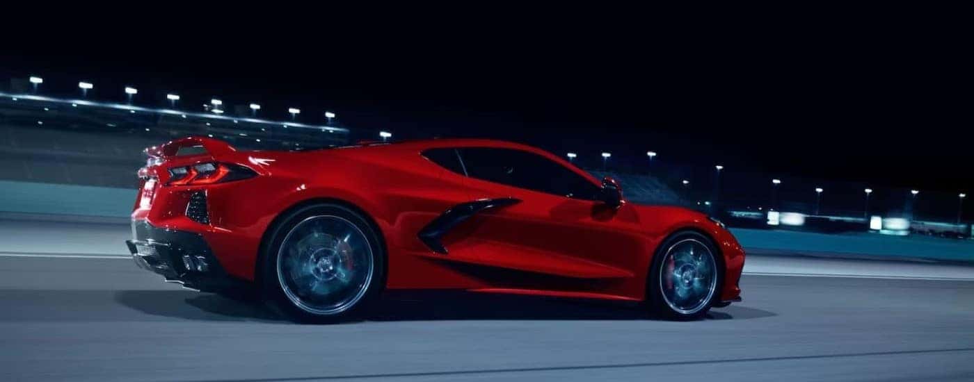 A red 2024 Chevy Corvette Stingray Z51 is shown on a racetrack at night.