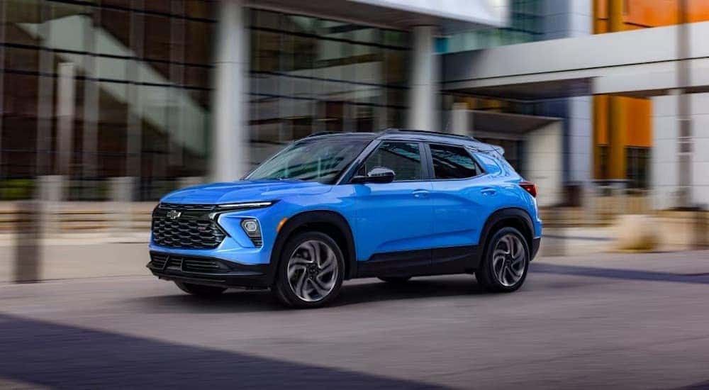 A blue 2024 Chevy Trailblazer RS driving by a building.