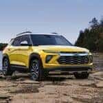 A yellow 2024 Chevy Trailblazer parked off-road on a lake shore.