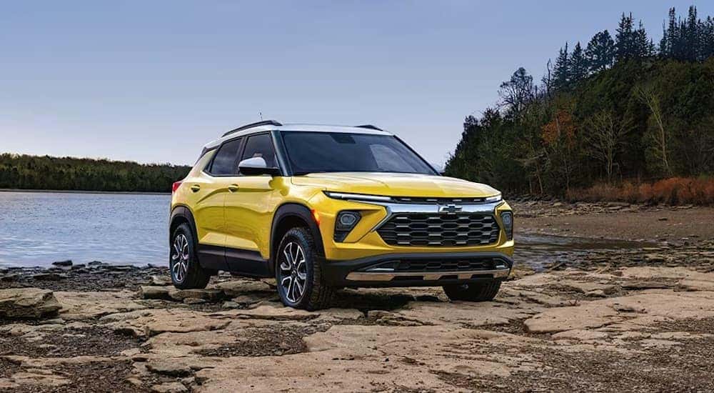 A yellow 2024 Chevy Trailblazer ACTIV parked off-road on a lake shore.
