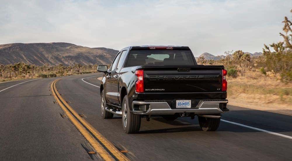 A black 2024 Chevy Silverado 1500 LT is shown from the rear at an angle.