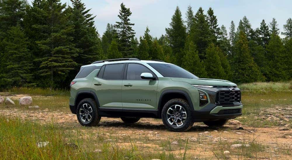 A sage green 2025 Chevy Equinox ACTIV parked in a field.