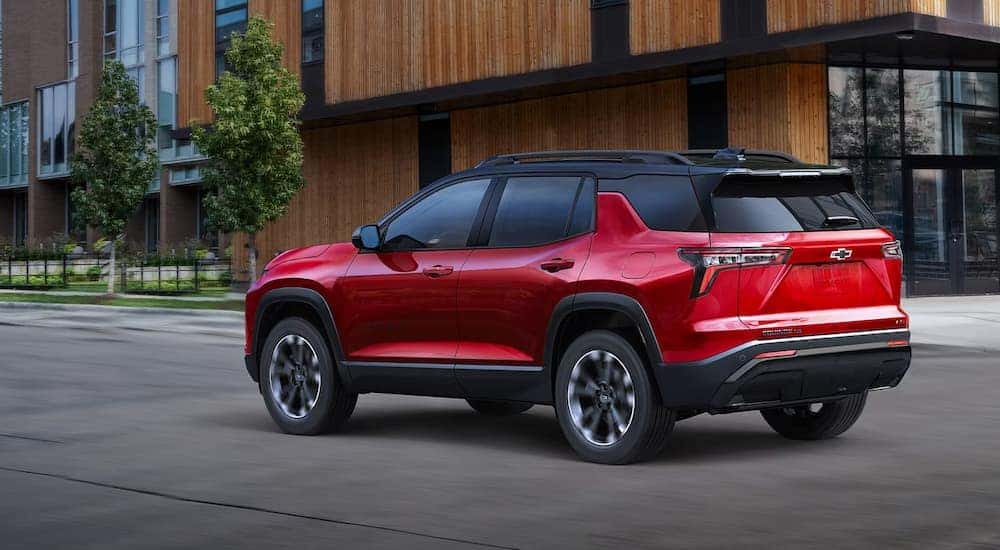 A red 2025 Chevy Equinox RS driving on a city street.