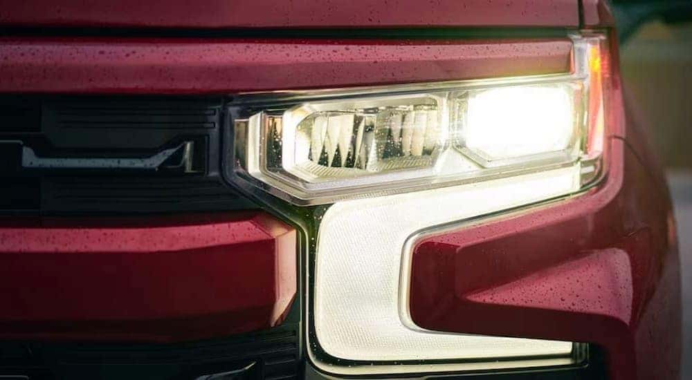 A close-up of the headlight on a red 2024 Chevy Silverado 1500 RST is shown.