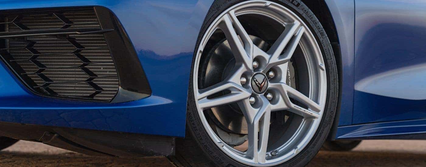 A close-up shows a silver rim on a blue 2025 Chevy Corvette Stingray