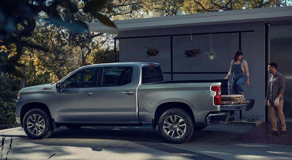 People loading building materials into the bed of a silver 2024 Chevy Silverado 1500 LT Z71.