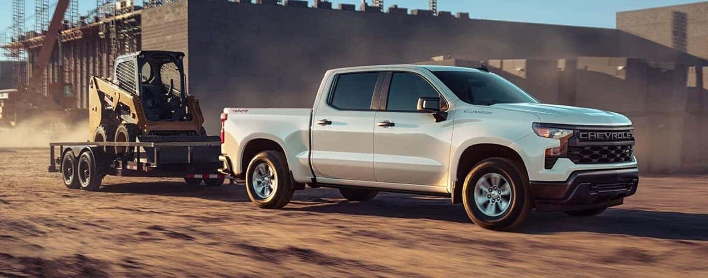 A white 2023 Chevy Silverado 1500 for sale near Sandy Springs is shown towing a trailer.