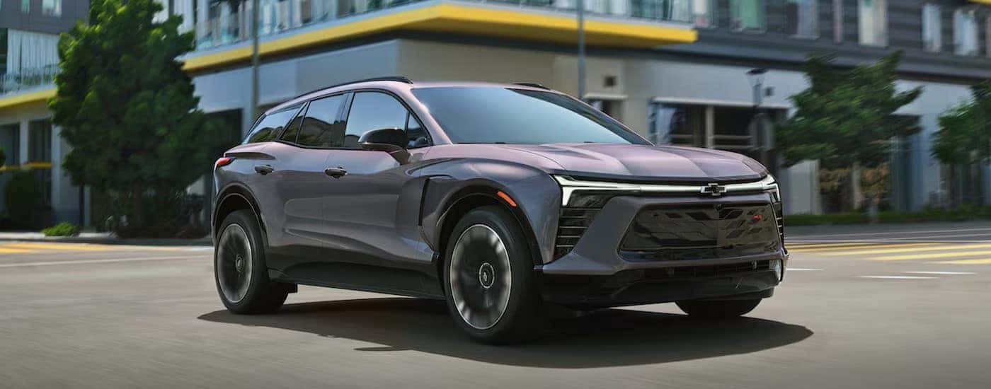 A silver 2025 Chevy Blazer RS EV is shown driving on a city street.