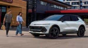 A white 2024 Chevy Equinox EV RS is shown parked near two people.