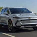 A grey 2025 Chevy Equinox EV driving down a road.