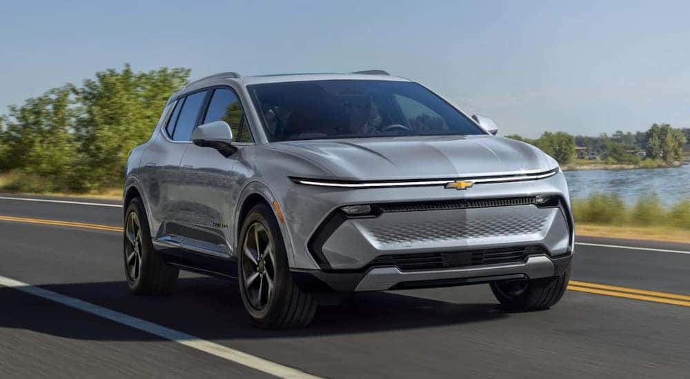 A grey 2025 Chevy Equinox EV driving down a road.