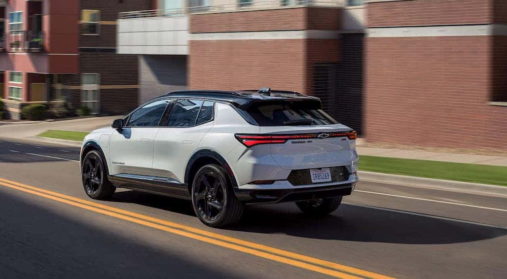 Rear angle view of a white 2025 Chevy Equinox EV RS driving.