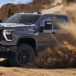 A grey 2025 Chevy Silverado 2500 HD ZR2 is off-roading on a sandy area.