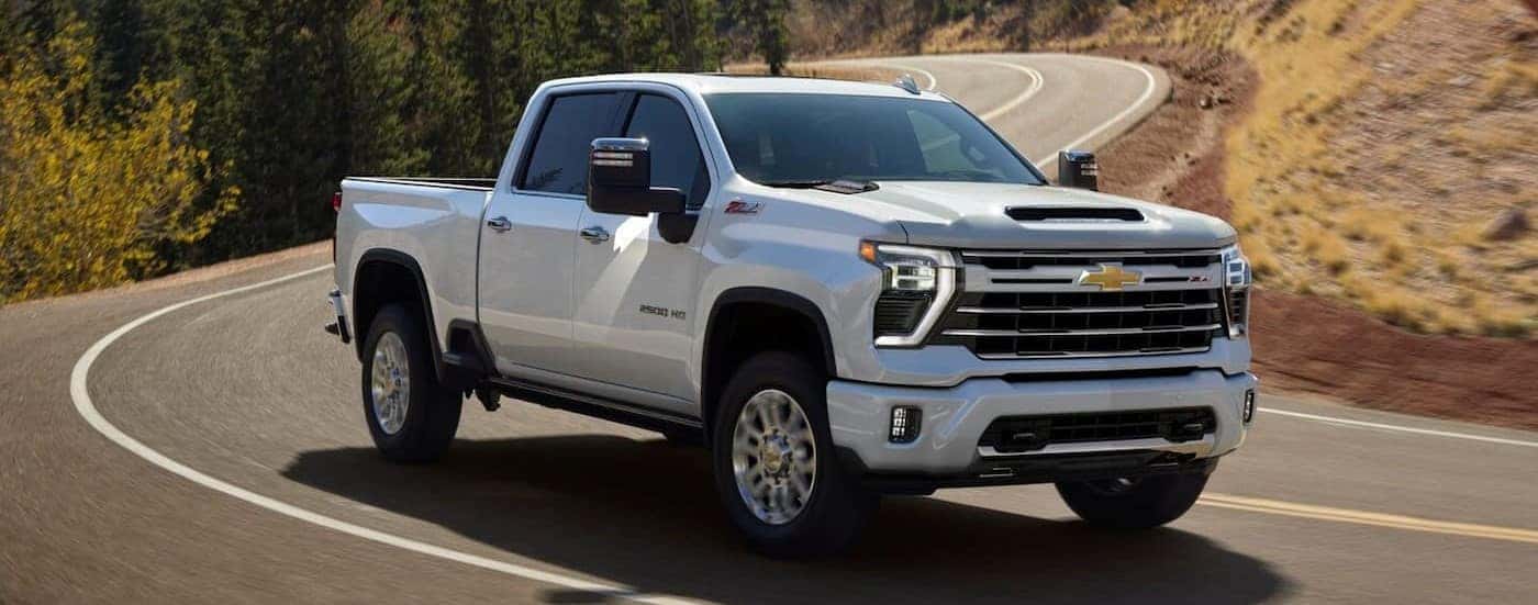 A white 2025 Chevy Silverado 2500 Z71 is shown driving on a highway.