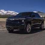 A black 2025 Chevy Silverado EV driving down a road.