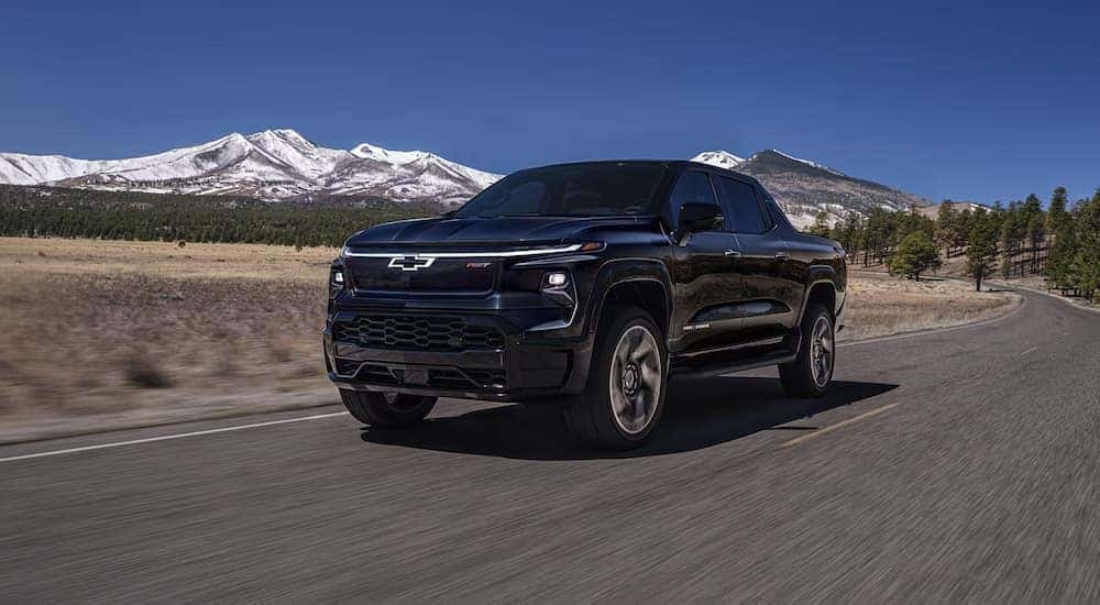 A black 2025 Chevy Silverado EV driving down a road.