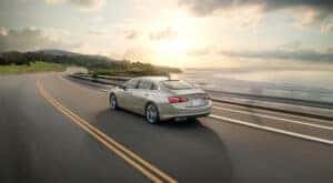 A tan 2024 Chevy Malibu is shown from the rear at an angle.
