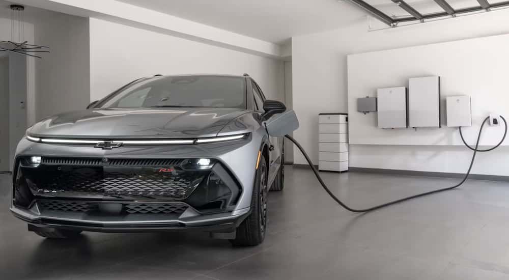 A grey 2025 Chevy Equinox EV parked in a garage and charging.