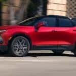 A red 2025 Chevy Blazer RS driving on a city street.