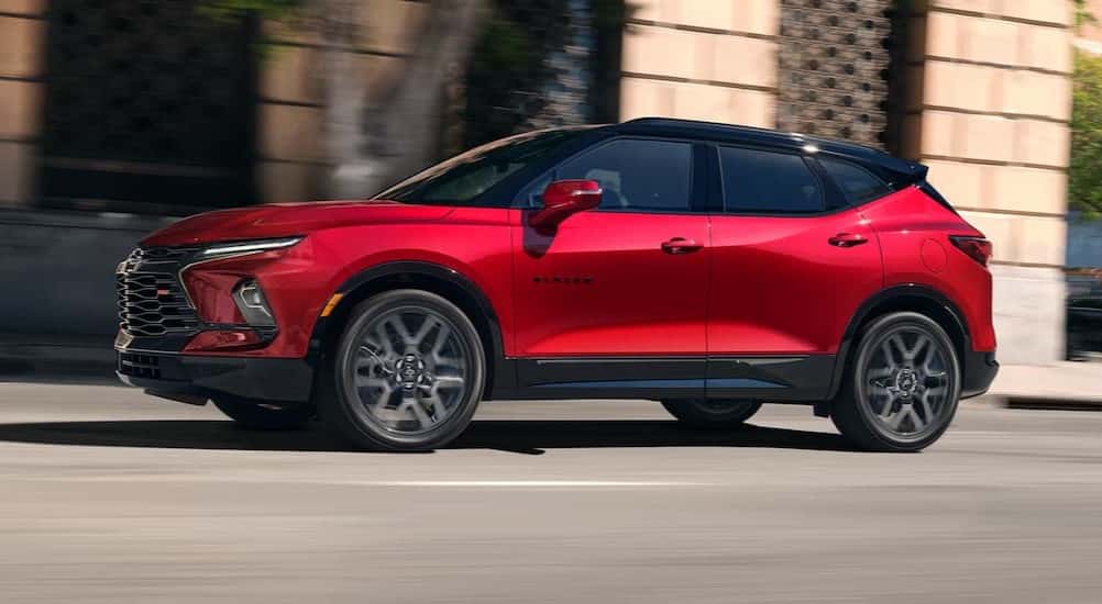 A red 2025 Chevy Blazer RS driving on a city street.