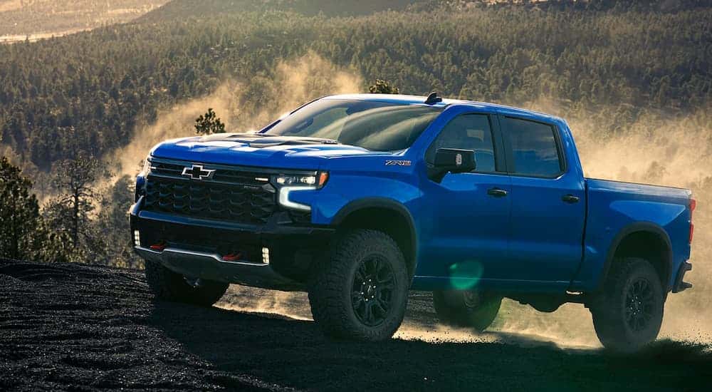 Blue 2025 Chevy Silverado 1500 ZR2 for sale in Atlanta driving up a dirt hill.