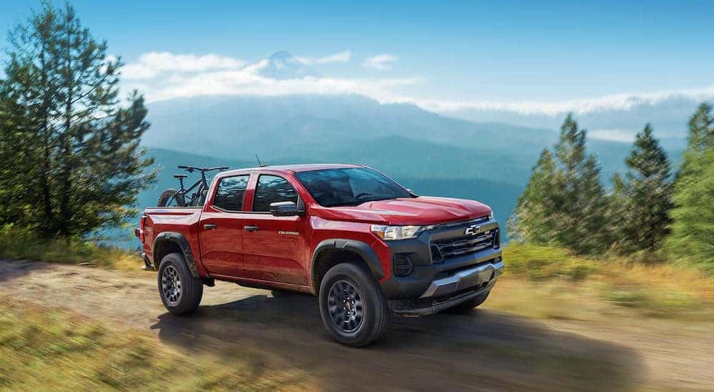 Red 2025 Chevy Colorado Trail Boss driving on a dirt road.