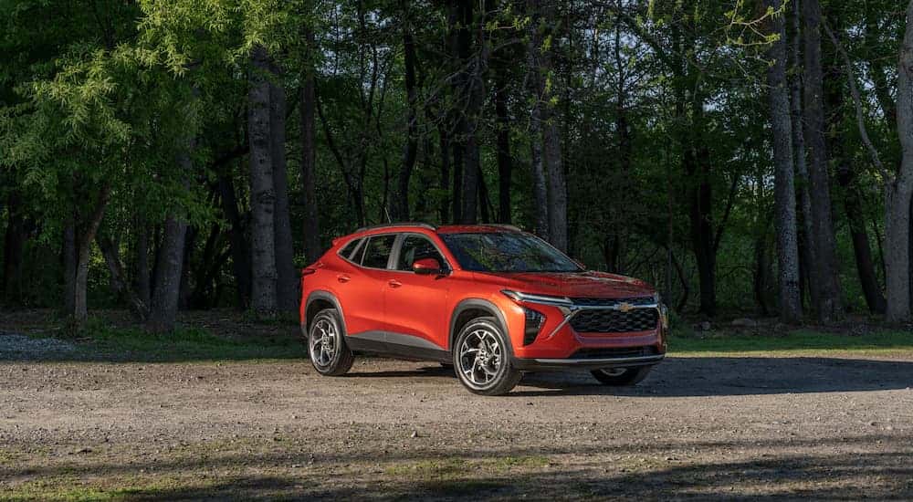 Orange 2025 Chevy Trax parked on dirt surrounded by trees