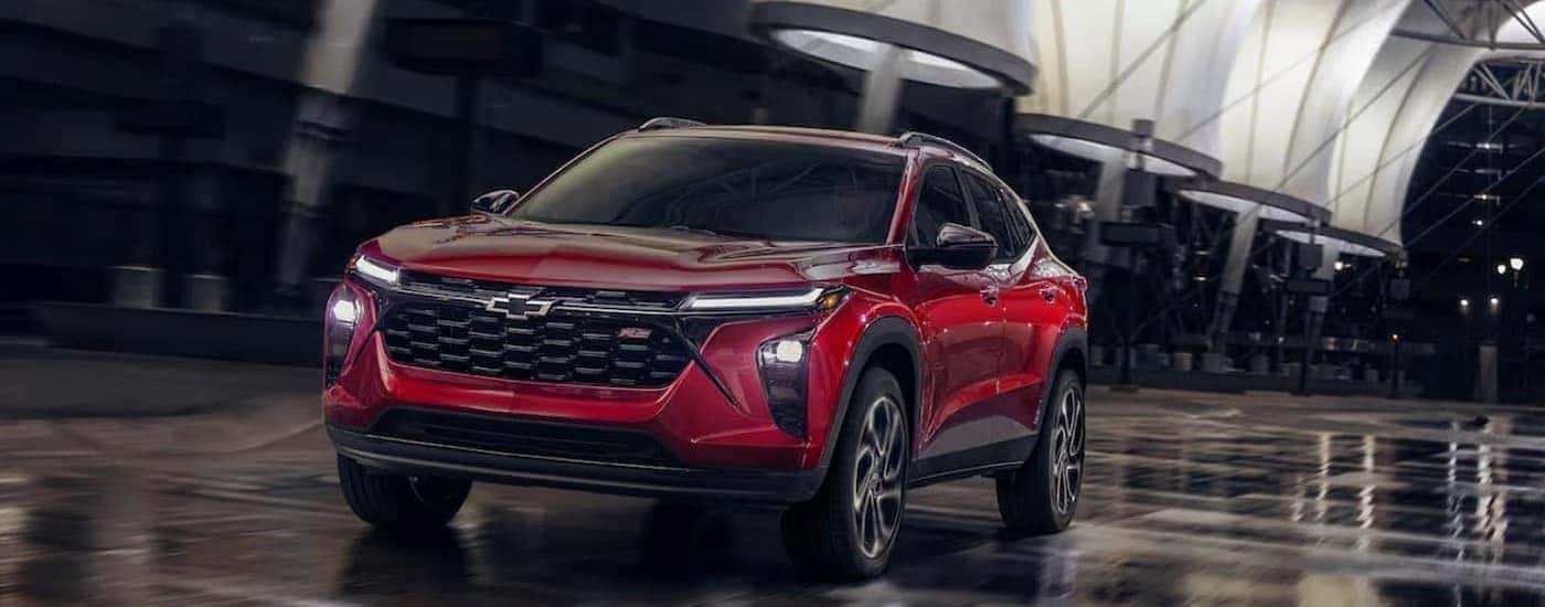 A red 2025 Chevy Trax RS driving in wet conditions.