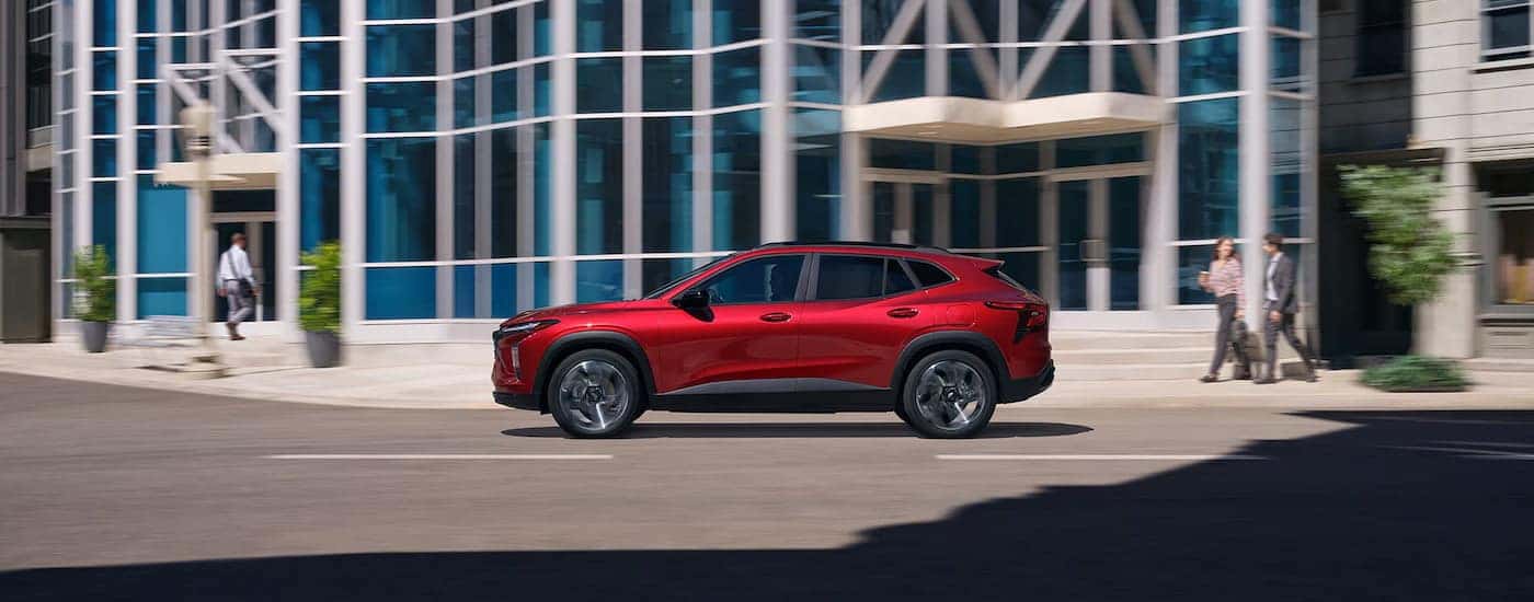 Red 2025 Chevy Trax RS driving down a street.