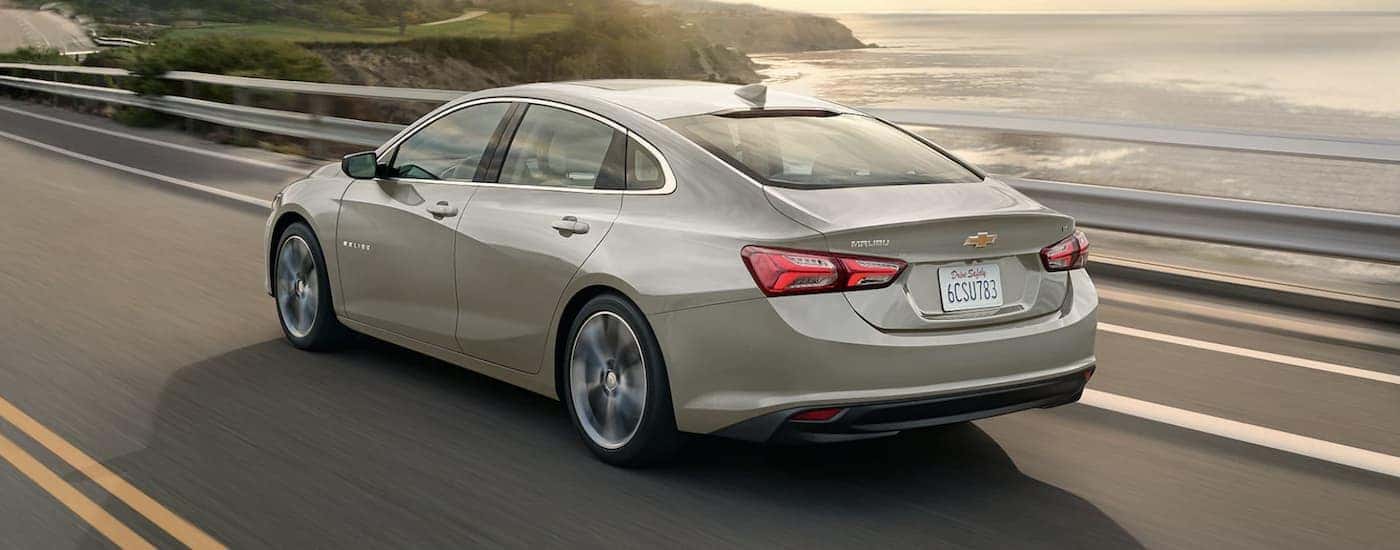 A tan 2024 Chevy Malibu is shown from the rear at an angle.