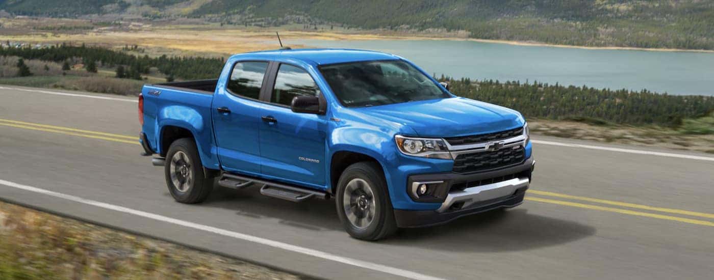 Blue 2022 Chevy Colorado Z71 driving down an open road from a dealer with work trucks for sale.