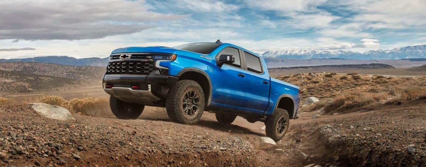 Blue 2024 Chevy Silverado 1500 ZR2 driving up a dirt hill.