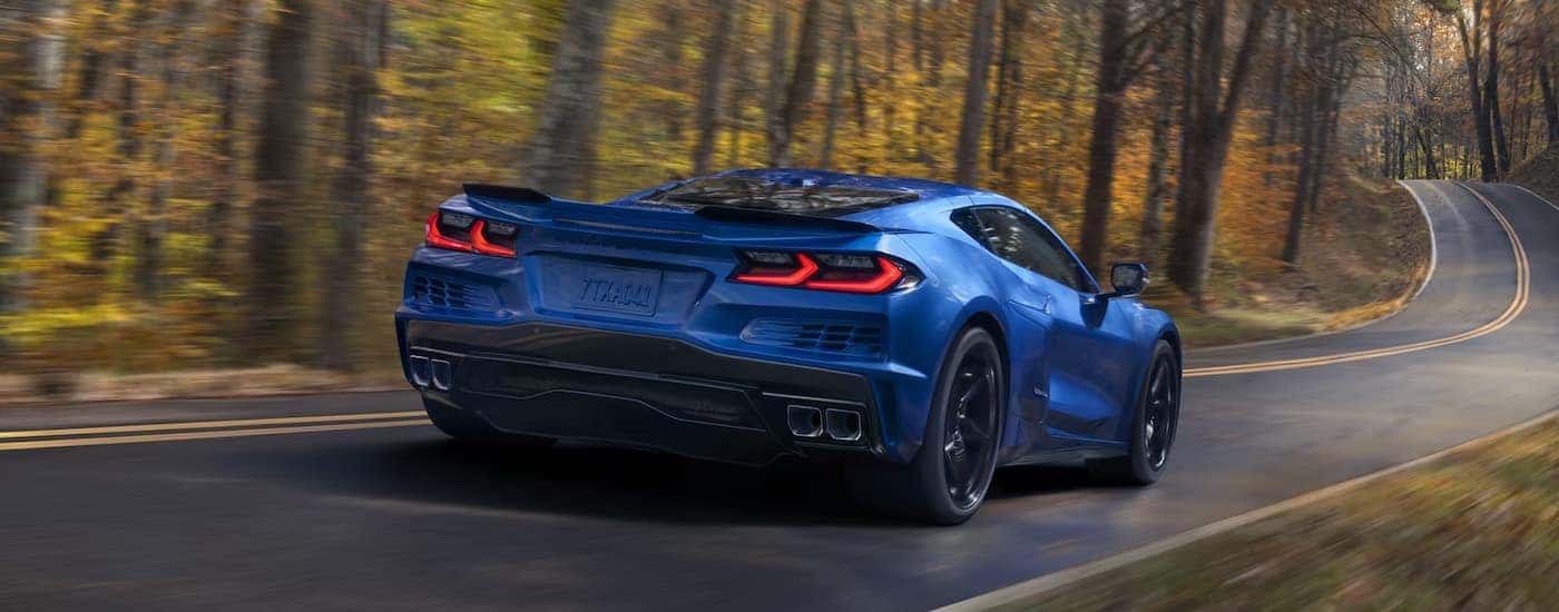 Blue 2025 Chevy Corvette E-Ray driving on a forest road