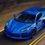 A blue 2025 Chevy Corvette E-Ray driving on a highway.