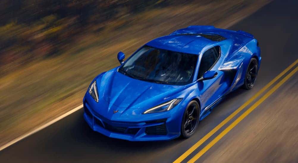 A blue 2025 Chevy Corvette E-Ray driving on a highway.