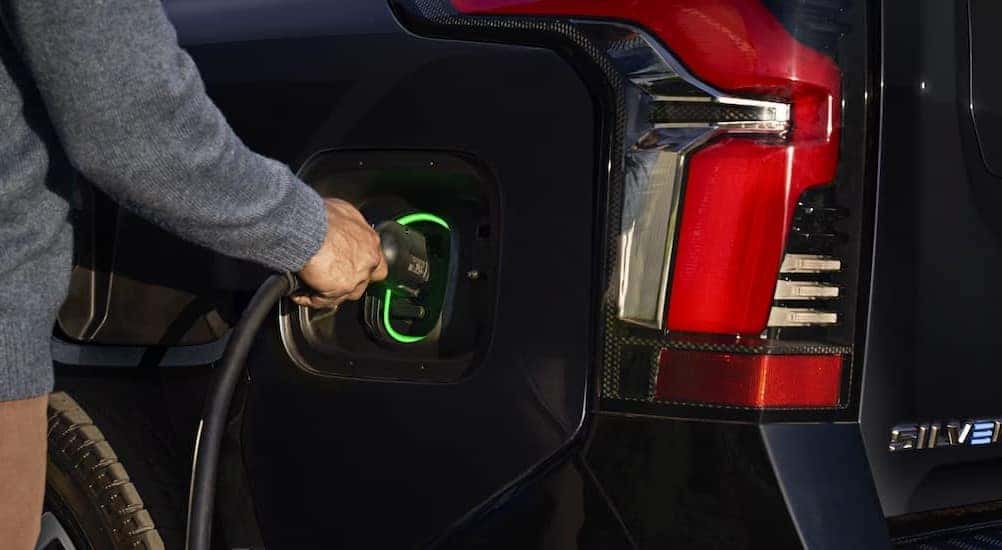Close-up of a person charging a blue 2025 Chevy Silverado EV.