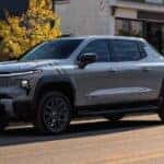 A silver 2025 Chevy Silverado EV for sale parked in a city.