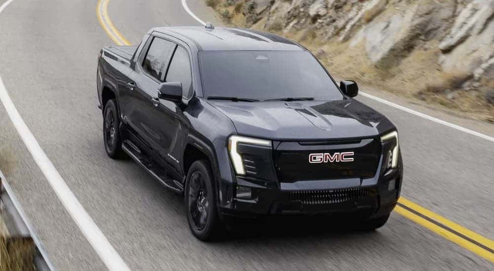 A black 2026 GMC Sierra EV driving down a highway