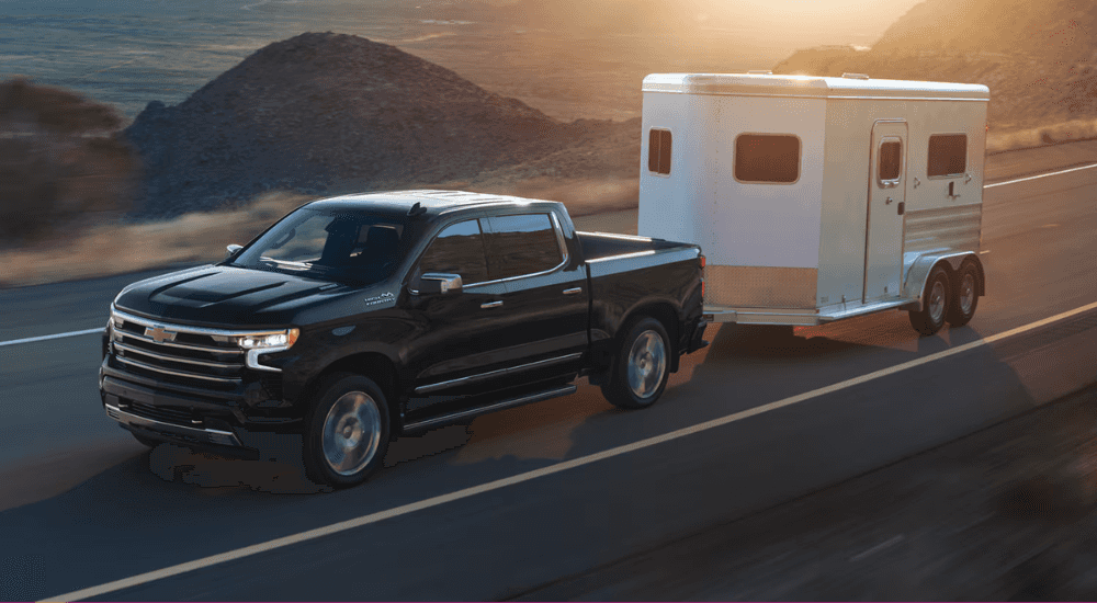 Black 2026 Chevy Silverado 1500 High Country LD towing a trailer to look at Silverados for sale near Marietta