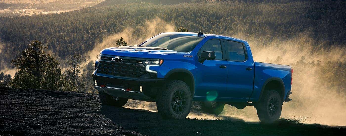 Blue 2025 Chevy Silverado 1500 ZR2 driving up a hill.