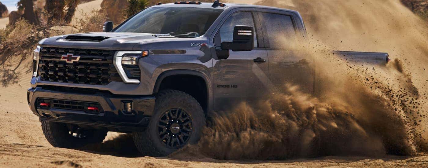 A gray 2026 Chevy Silverado 2500 HD ZR2 off-roading in sand