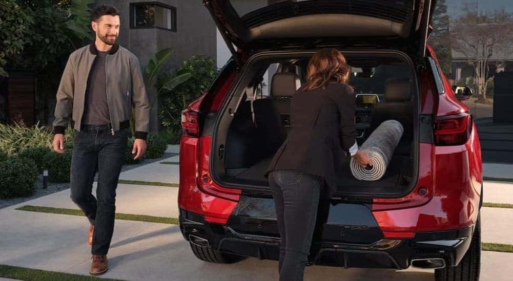 People loading a carpet into the cargo area in a red 2026 Chevy Blazer.