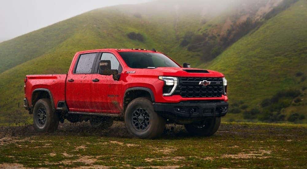 Side of a red 2025 Chevy Silverado 3500 HD parked off-road.