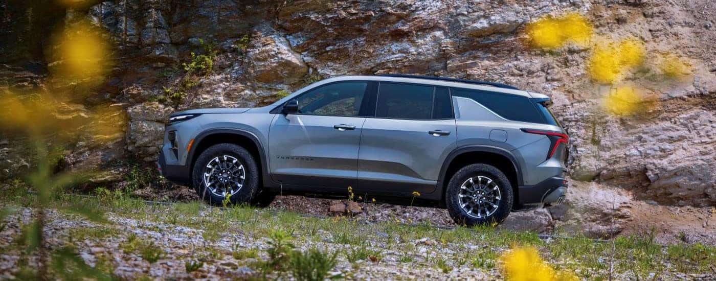 Side of a silver 2026 Chevy Traverse parked off-road.